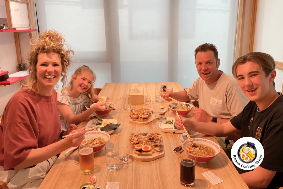 Una famiglia con un bambino piccolo e un adolescente condivide un ramen in un corso di cucina per famiglie a Tokyo