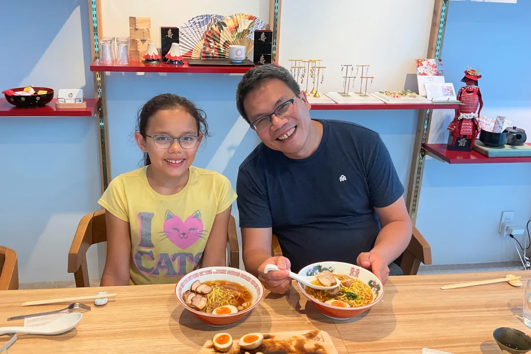 Father and daughter enjoying their completed ramen bowls
