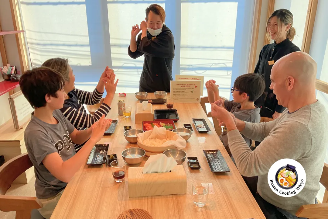 Una famiglia segue la dimostrazione pratica della chef durante un corso di cucina a Tokyo