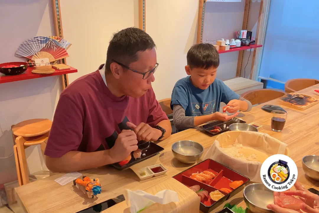 Padre e giovane figlio modellano sushi insieme in un corso di cucina per famiglie a Tokyo