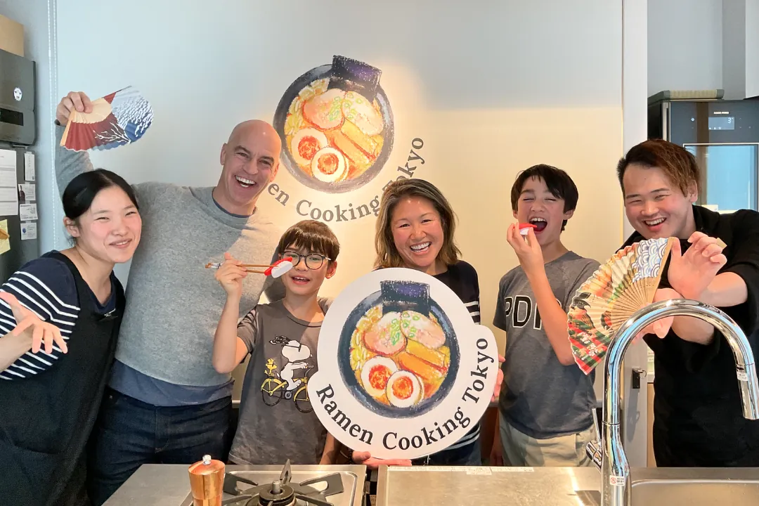 Un gruppo familiare allegro festeggia dopo il corso di cucina di ramen e sushi a Tokyo