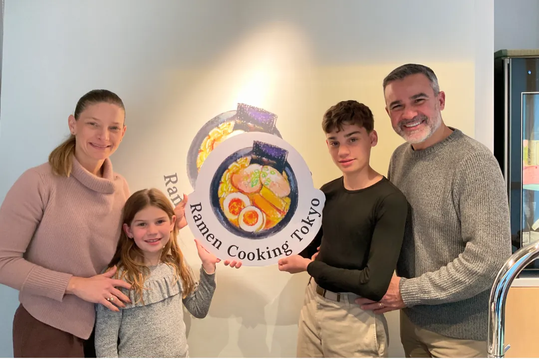 Famiglia di quattro in posa dopo il corso di cucina di ramen e sushi a Tokyo