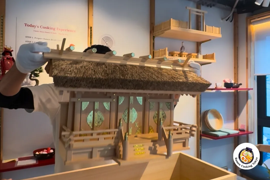 The kamidana emerges fully from the paulownia box, handled with care by the miyadaiku