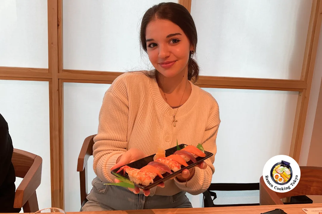 A solo traveler holding a finished sushi platter at a Tokyo class